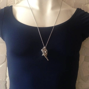 Silver cowboy pistol and hat pendant necklace shown on model wearing dark blue t-shirt