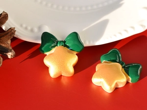 Close-up of golden star resin accessories with green bows for DIY crafts decoration