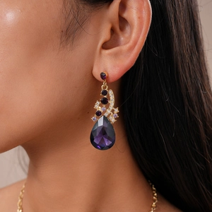Close-up of a luxury gold-plated earring with purple pear-cut crystal and diamonds