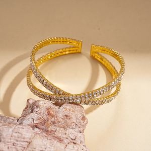 Macro detail of gold-plated double-row open cuff bracelet with sparkling crystal accents