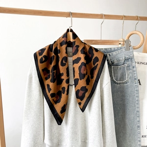 Detailansicht eines Seidenschals mit Leopardenmuster, schwarzem Saum und glatter Textur