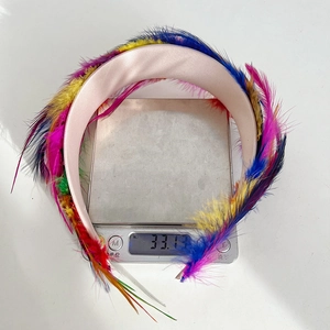 Detailed view of colorful feather headband on scale weighing approximately 33 grams