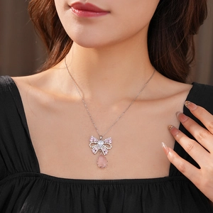 Detail of bow and pink teardrop pendant necklace worn by a model for a vintage look