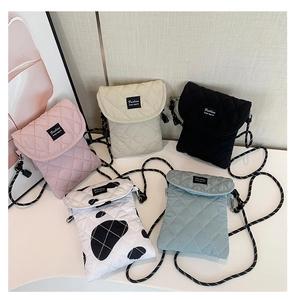 Close-up of quilted crossbody phone bags in pink, beige, black, cow print and light blue