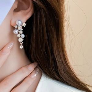 Close-up of elegant leaf-shaped silver earrings with long tassels and pearls on a model