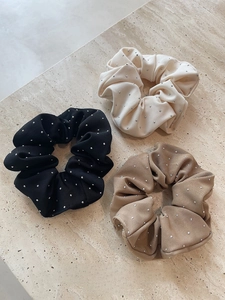 Detailed view of three elegant scrunchies in black, beige, and khaki with silver rhinestones