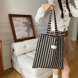 Detail of striped canvas tote bag showing thick fabric texture and woven brand label