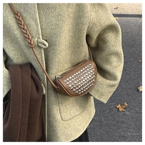 Detail of brown litchi pattern leather crossbody bag with silver rivet studs and woven strap