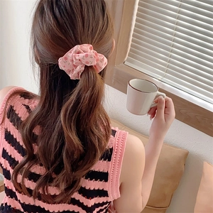 Detail view of pink floral scrunchie worn on a ponytail in a cozy setting