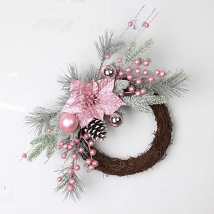 Pink Christmas wreath with pine needles and glitter flowers on a white wall