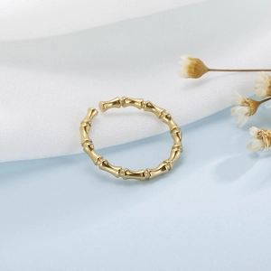 Macro shot of gold bamboo joint ring with adjustable open band on textured fabric