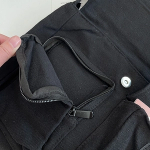 Detail of black canvas tote showing secure zipper pocket and magnetic snap closure
