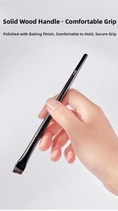 Detailed close-up of model holding the A-102 angled eyeliner brush with solid wood handle