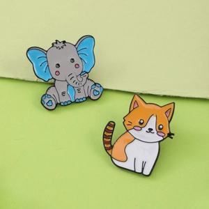 Cute cartoon enamel pins featuring a grey elephant and striped cat on green background
