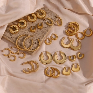 Flat lay of chunky gold hoop earrings on silk fabric and stone for a luxury look