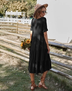 Détails d'une robe midi noire bohème avec jupe à volants et découpe dans le dos élégante