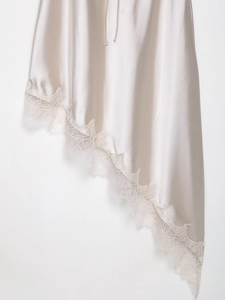 Detail shot of the champagne silk dress featuring delicate lace trim and irregular hemline