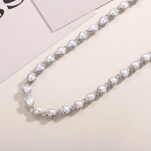Detailed view of silver heart links inlaid with pearls on a delicate choker necklace