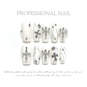Detail of white marble press-on nails with silver gothic cross and pearl accents