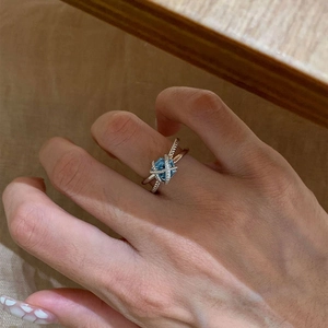 Detail of cross silver ring with blue gemstone and twisted band on a finger