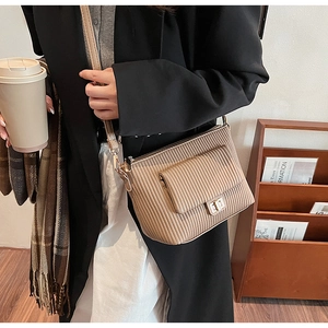 Detail view of light brown quilted crossbody bag with vertical stitching and gold clasp