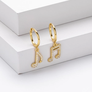 Detail view of gold music note earrings with sparkling white cubic zirconia stones