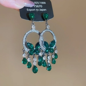 Close-up of vintage heart earrings with green crystal tassels and butterfly detail