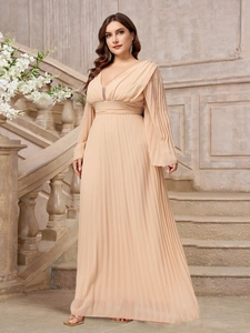 Detail of elegant V-neck apricot pleated evening gown with long sleeves on a stone staircase