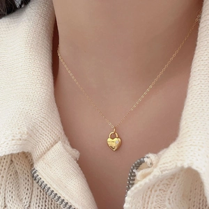Close-up of golden heart lock pendant with zircons and for me engraving on a knit sweater