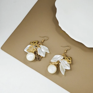 Detailed macro of vintage white petal earrings with hollow gold butterfly and pearl charms