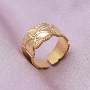 Macro detail of gold-plated geometric embossed texture on adjustable stainless steel ring