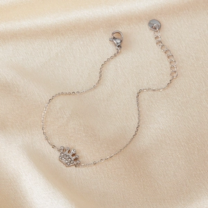 Detail of silver crown bracelet with zircons and S925 tag on silk background