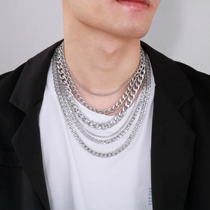 Close-up of layered silver titanium steel necklaces with Cuban links on male model