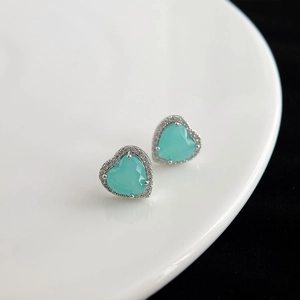 Gros plan de boucles d'oreilles cœur en turquoise avec halo de zircon sur céramique