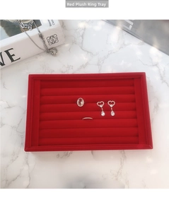 Détail d'un plateau à bijoux en velours rouge avec fentes pour bagues et boucles d'oreilles