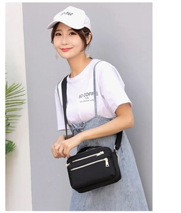Close-up of waterproof nylon crossbody bag with three gold zipper compartments
