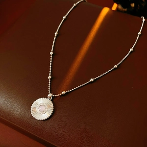 Détail d'un collier pendentif marguerite en argent avec pierre rose sur cuir marron