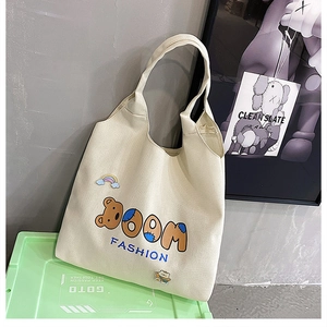 Detail der cremefarbenen Canvas-Tasche mit süßem Bären-Patch und BOOM-Stickerei