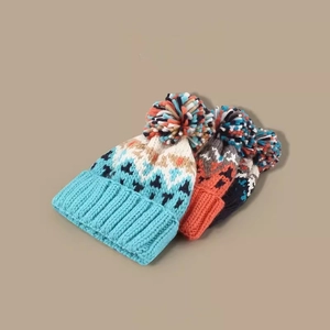 Three warm knitted beanies with colorful pom poms in blue and red tones for winter