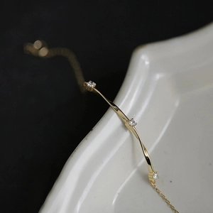Macro shot of gold-plated silver Mobius bracelet with three inlaid zircon accents