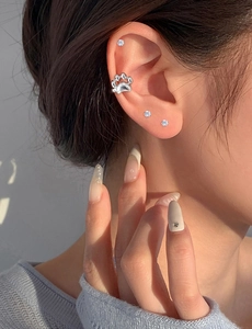 Close-up of a silver cat paw ear cuff and sparkling zircon studs worn on a model ear
