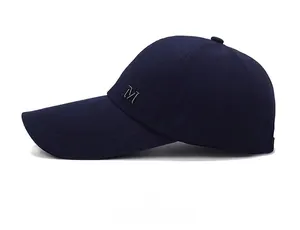 Détail d'une casquette de baseball en toile bleu marine avec logo M en métal de profil