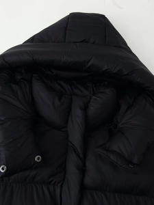 Detail of hooded black puffer jacket with silver snap buttons and smooth quilted fabric
