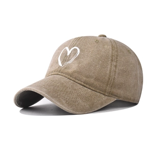 Detail of khaki washed cotton baseball cap featuring a white hand-drawn heart embroidery