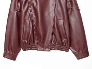 Detail of wine red faux leather jacket featuring elastic hem and side pocket design