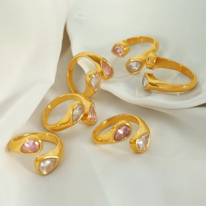 Golden titanium steel rings featuring pink and white teardrop zircons on white silk