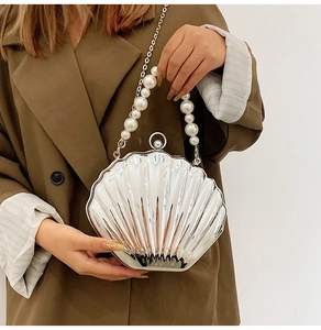 Macro shot of silver shell bag with pearl handle and metallic chain on brown blazer