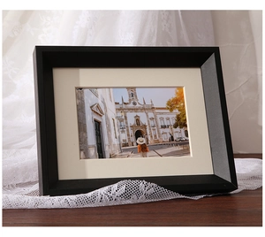 Detail of a modern black solid wood photo frame with cream matting on a wooden desk
