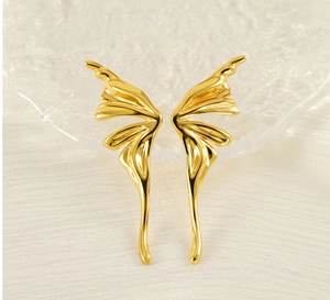 Macro detail of golden butterfly wing earrings with polished finish on glass texture