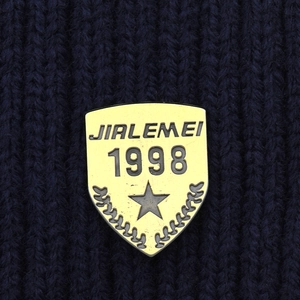Macro detail of the yellow crest patch on a thick navy blue ribbed knit winter hat